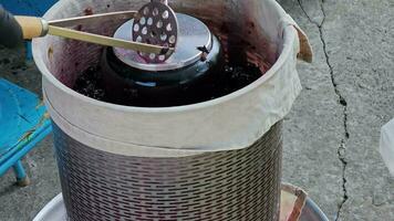 The process of making homemade grape wine. Grapes are pressed in a hydraulic press. Grape juice flows into a container. video
