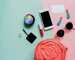 plano de una linda bolsa de mujer rosa abierta con cosméticos, accesorios, tarjeta de etiqueta y teléfono inteligente en un fondo colorido con espacio para copiar foto