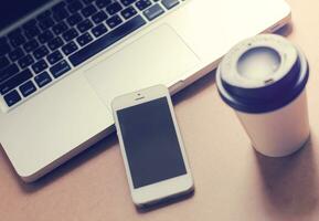 Smart phone and notebook computer with coffee cup, retro filter style toned photo