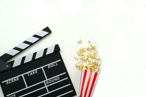 Clapperboard or movie slate black color with popcorn on white background. Cinema industry, video production and film concept. photo
