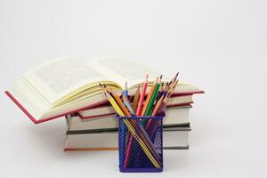 Crayon or colored pencils in box and the book placed in the blurred background. Knowledge and education concept. photo