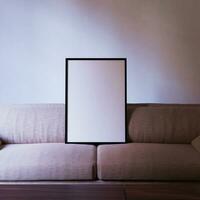 minimalist frame mockup poster standing on the sofa in the living room with white wall background photo