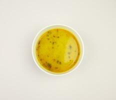 matthe ke aaloo this is a indian dish A bowl of yellow soup with a green leaf on it photo