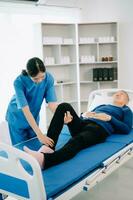 Physiotherapist Helping Patient While Stretching His Leg in bed in clinic photo