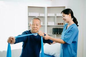 Physiotherapist Helping Patient While Stretching His Leg in bed in clinic photo