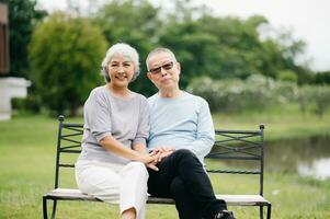 Asian senior couple having a good time. They laughing and smiling while sitting outdoor at the park. Lovely senior couple photo