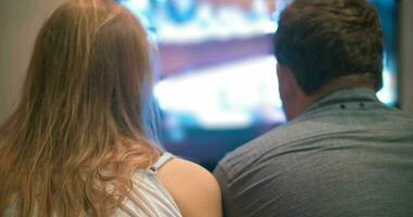 Young man and woman watching television at home video