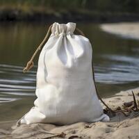 a white bag sitting on the sand near a river. . photo