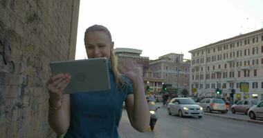 Young woman with pad having video chat outdoor