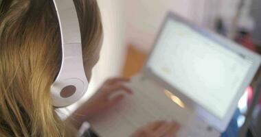 kvinna i hörlurar använder sig av bärbar dator video