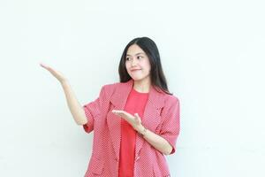 portrait of beautiful asian woman wearing red outfit pointing to the side for copy space with smiling gesture photo