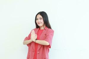 retrato de hermosa asiático mujer vistiendo rojo atuendo con namaste gesto mientras sonriente foto