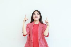 portrait of beautiful asian woman wearing red outfit pointing up for copy space with smiling gesture photo