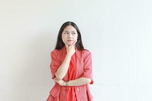 portrait of beautiful asian woman wearing red outfit with thinking expression photo