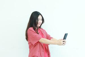 portrait of beautiful asian woman wearing red outfit looking at mobile phone with happy expression photo