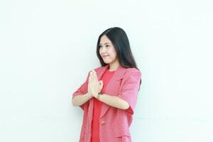 retrato de hermosa asiático mujer vistiendo rojo atuendo con namaste gesto mientras sonriente foto