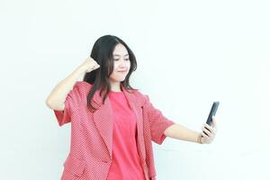 portrait of beautiful asian woman wearing red outfit looking at mobile phone with happy expression photo