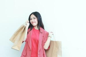 portrait of beautiful asian woman wearing red outfit gesturing carrying lots of shopping bags with happy expression photo