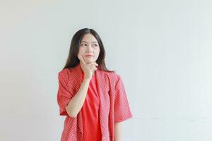 portrait of beautiful asian woman wearing red outfit with thinking gesture photo