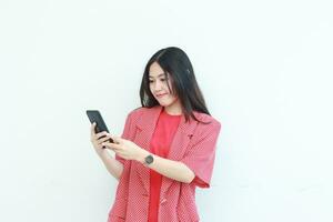 portrait of beautiful asian woman wearing red outfit while holding mobile phone with happy expression photo