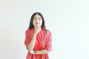 portrait of beautiful asian woman wearing red outfit with thinking gesture photo