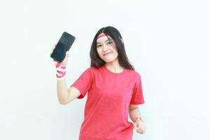 retrato de hermosa asiático mujer vistiendo rojo atuendo celebrando Indonesia independencia día participación móvil teléfono y sonriente foto