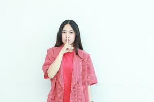 portrait of beautiful asian woman wearing red outfit with gesture to be quiet photo