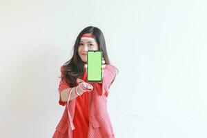 portrait of beautiful asian woman wearing red outfit celebrating Indonesia independence day holding mobile phone and smiling photo