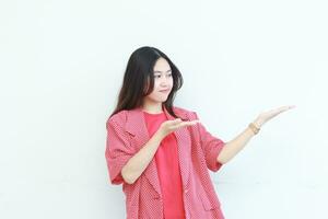 portrait of beautiful asian woman wearing red outfit pointing to the side for copy space with smiling gesture photo