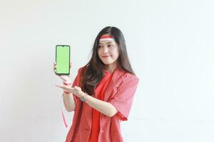 portrait of beautiful asian woman wearing red outfit celebrating Indonesia independence day holding mobile phone and smiling photo