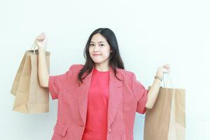 portrait of beautiful asian woman wearing red outfit gesturing carrying lots of shopping bags with happy expression photo