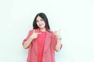 portrait of beautiful asian woman wearing red outfit pointing to the side for copy space with smiling gesture photo