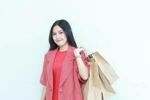 portrait of beautiful asian woman wearing red outfit gesturing carrying lots of shopping bags with happy expression photo