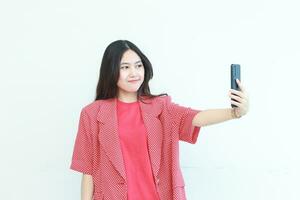 portrait of beautiful asian woman wearing red outfit looking at mobile phone with happy expression photo