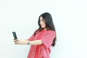 portrait of beautiful asian woman wearing red outfit looking at mobile phone with happy expression photo