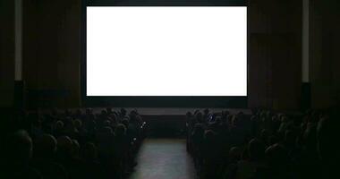 espectadores en oscuro cine salón con blanco pantalla video