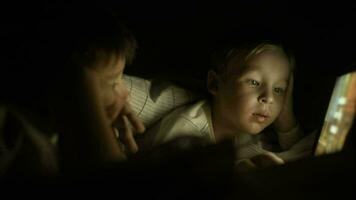 dos Niños acostado en cama a noche y utilizando almohadilla video