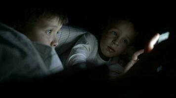 Two little boys try to watch the film at night using tablet video