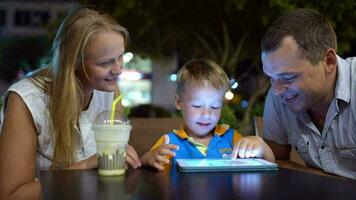 jongen gebruik makend van tablet pc zittend in cafe met ouders video