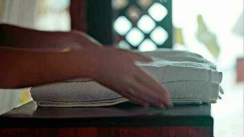 Woman putting fresh towels on the table and flower on it video