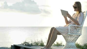 Woman near the sea watching photos using pad video