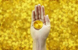 Gold coins in hand against a pile of gold coins in the background photo