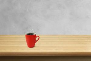 Red coffee cup on wooden table with cement wall in the background photo