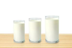 Three glasses of milk on wooden table isolated on white background photo