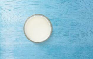 Milk in glass. Top view. On blue wooden background. photo