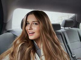 Young woman with long hair, wavy hairstyle in the car or taxi cab as passenger, exploring the city, transport and travel photo