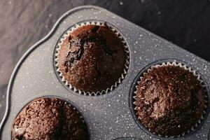 Just baked chocolate muffins in tray, homemade comfort food recipe photo