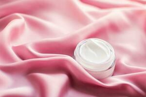 Luxury face cream jar on a soft pink silk photo