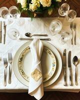 Elegant dinner table setting arrangement in English country style as flatlay tablescape, folded napkin on a serving plate, tableware and holiday table decor, generative ai photo