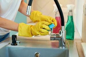 Woman cleaning kitchen sink with water tap photo